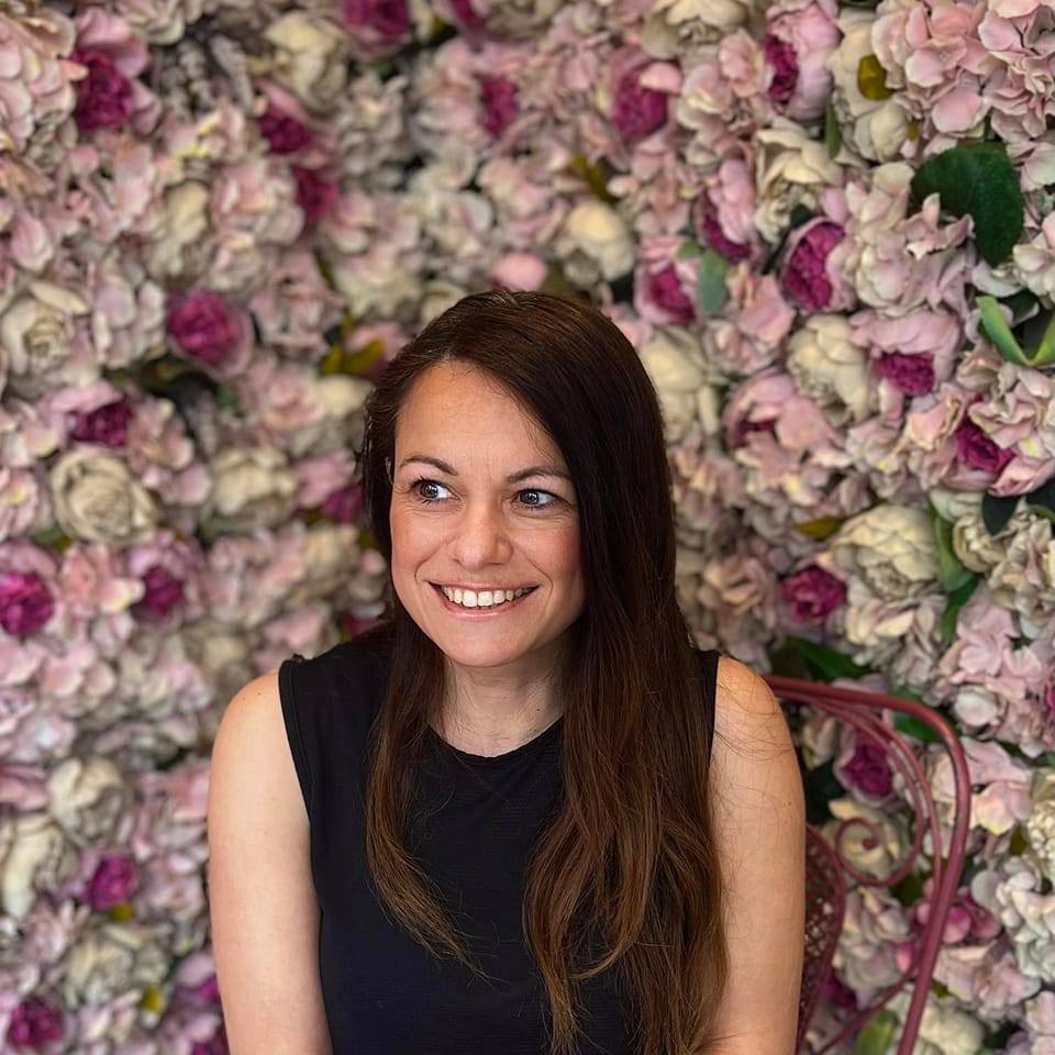 OnenessHub founder in front of a background full of pink and purple roses